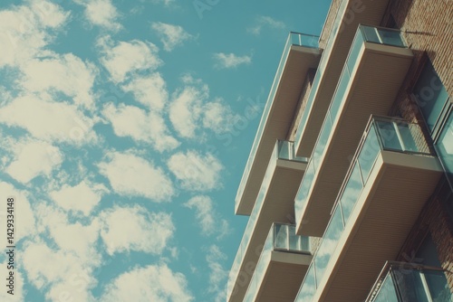 Modern apartment building exterior with balconies against a partly cloudy sky photo