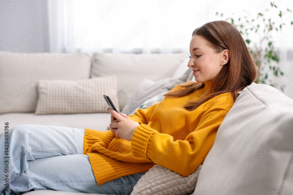 Teenage girl using smartphone on sofa at home Teenage girl using smartphone on sofa at home