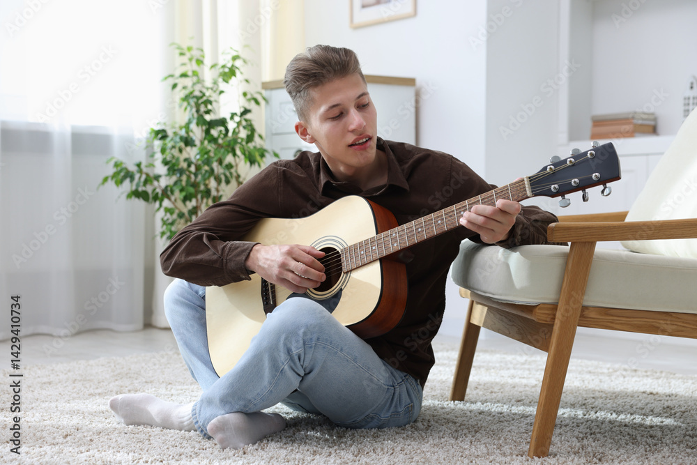 Happy man playing guitar on floor indoors
