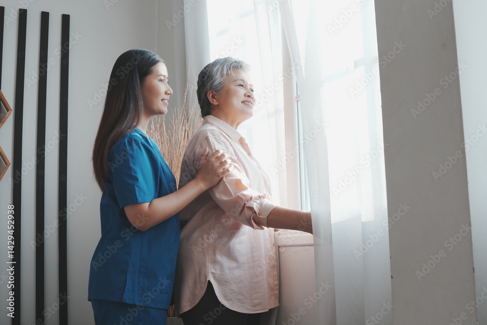 An elderly Asian woman stands at her bedroom window looking and thinking about things and an Asian nurse is taking care of her in a nursing home in the morning.