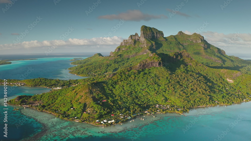 Stunning aerial view of Bora Bora island, French Polynesia, showcasing the iconic mount Otemanu, turquoise lagoon, lush green vegetation, and idyllic overwater bungalows during a sunny day