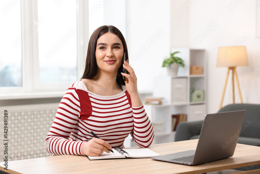 Beautiful woman with planner talking on smartphone at wooden table indoors Beautiful woman with planner talking on smartphone at wooden table indoors