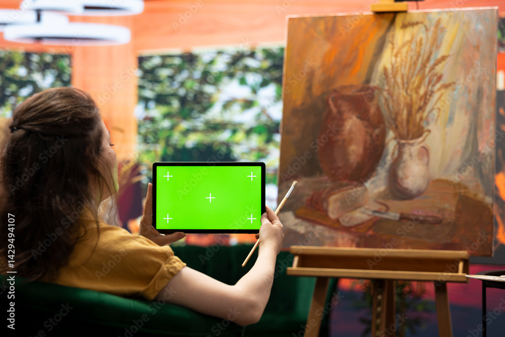 Painter admiring her creative masterpiece in art studio next to green screen, finishing her oil paint mixed with watercolor artwork. Creative artist enjoying quality time in her atelier.