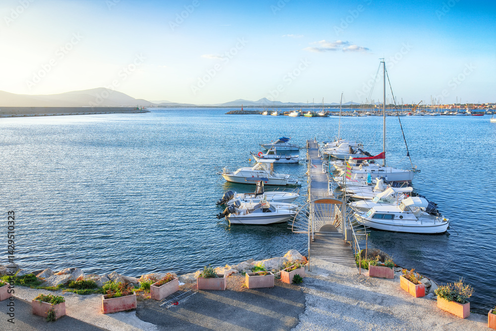 Unbelivable summer view of the Alghero Marina yacht port at the Gulf of Alghero with anchored sailboats.
