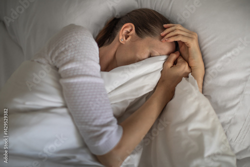 Young depressed sleepless woman lying in bed waking up tired from lack of sleep 