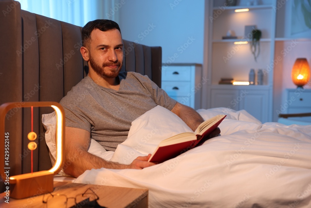 Fototapeta premium Young man with book in bed at home