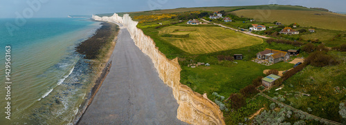 Obraz na płótnie Birling Gap in East Sussex, UK, with chalk cliffs, beach access stairs, parked cars, and visitors exploring the dramatic coastline and tidal shore w salonie