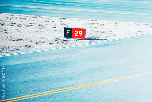 Obraz na płótnie Runway marker sign stands beside with yellow lines, casting a shadow on the gravel edge. Light-blue runway surface extends into the distance, indicating airport area w salonie