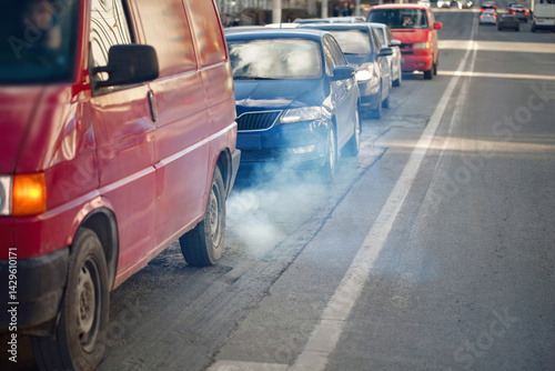 Obraz na płótnie Smoke rises from van exhaust in line of cars, impact of vehicle emissions and air pollution. City traffic emits vehicle exhaust into the air, harmful emissions. Tailpipe smoke. Selective focus. w salonie