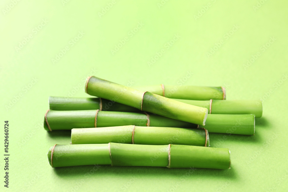 Fototapeta premium Cut bamboo stems on light green background, closeup