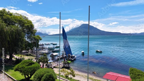 Beautiful cinematic aerial view os the Panajachel town surrounded by Toliman and Atitlan volcanoes, next to the Atitlan lake its piers and traditional fisher and tourist boats - Guatemala