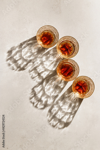 Obraz na płótnie Whiskey Glasses with Shadows and sunlight Reflection on beige background, minimal aesthetic top view summer still life, refraction throug crystal shine cups, caustics effect, vertical w salonie