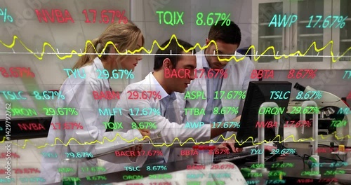 Three lab scientists typing and examining financial data on screen with floating stock symbols