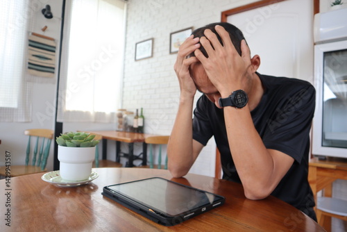 The young man in a black shirt is stressed out at the desk.