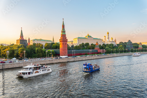 View of Kremlin with Vodovzvodnaya tower, Grand Kremlin Palace from repaired Bolshoy Kamenny Bridge in Moscow city on sunny summer day. Cruise ship sails on the Moscow river