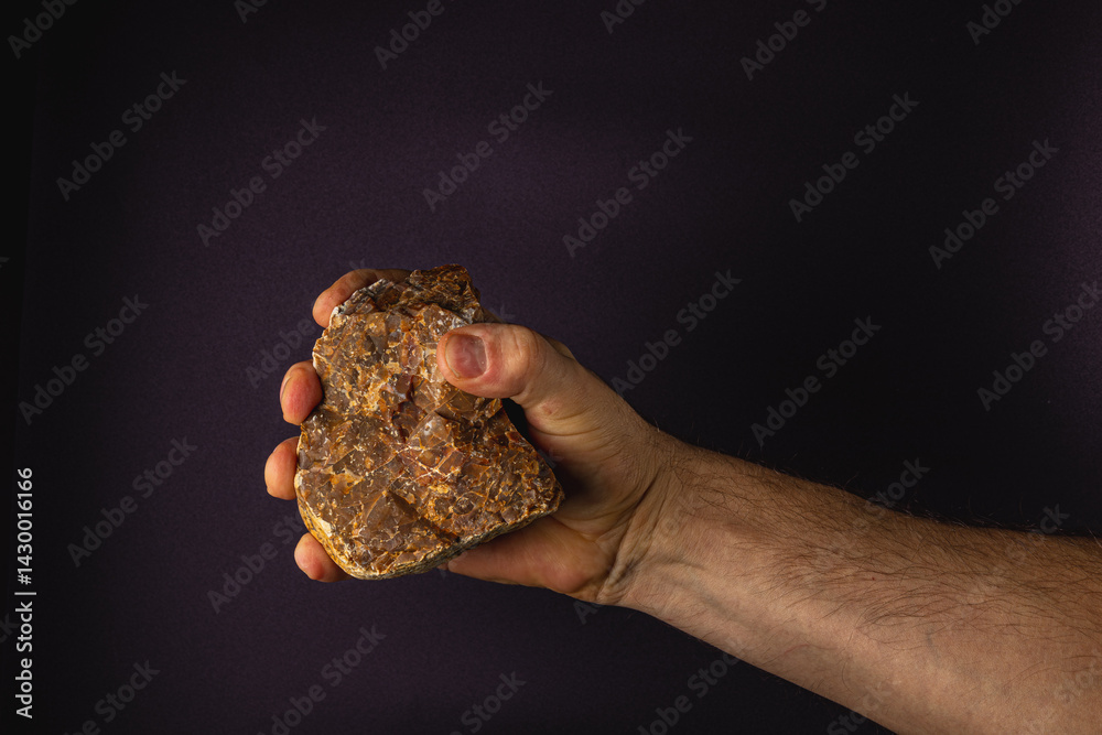 Holding a textured rock in a hand against a dark background