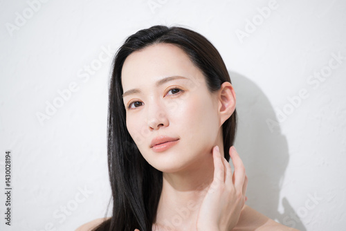 黒髪が美しい若い女性の艶と素肌感が美しい手を添えるビューティーイメージのカメラ目線でアンニュイな表情