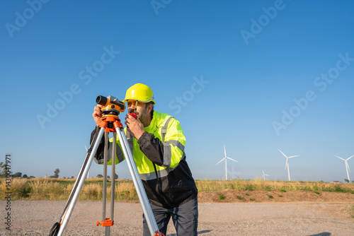 Engineer wearing uniform inspection and survey work in wind turbine farms rotation to generate electricity energy. Maintenance engineer working in wind turbine farm at sunset.