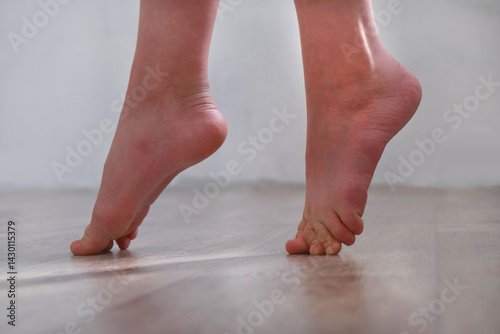 Barefoot teenage girl, dancer artist standing on tiptoe. Low section. Dance studio, tiptoe legs, position, practicing in ballet studio. Contemporary