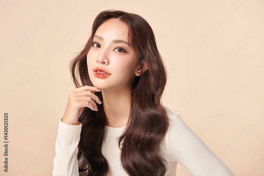 Fototapeta premium A beautiful young Asian woman with clean, fresh skin against a beige background. Skincare, facial treatment, cosmetology, beauty, and spa. An elegant portrait of an Asian woman.
