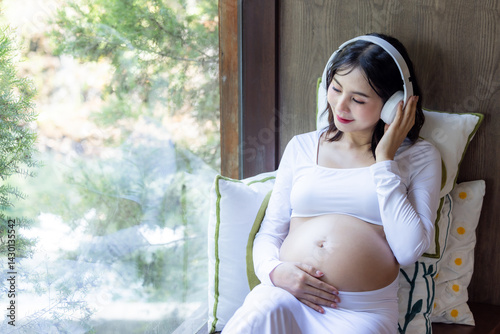 Obraz na płótnie Happy asian pregnant woman listen music and lying, Asian pregnant woman use headphones listen music for baby in belly learn and feeling relax, Pregnant woman with headphone, Motherhood and Pregnancy. w salonie
