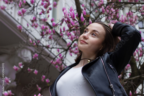 Obraz na płótnie Portrait of a pretty young brunette woman with brown eyes under blooming pink magnolia flowers w salonie