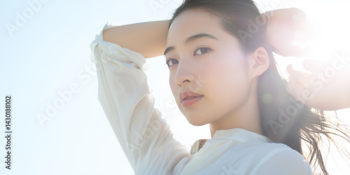 白いシャツの女性が逆光の中で見つめる美しい姿