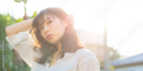 白いシャツの女性が逆光の中で見つめる美しい姿