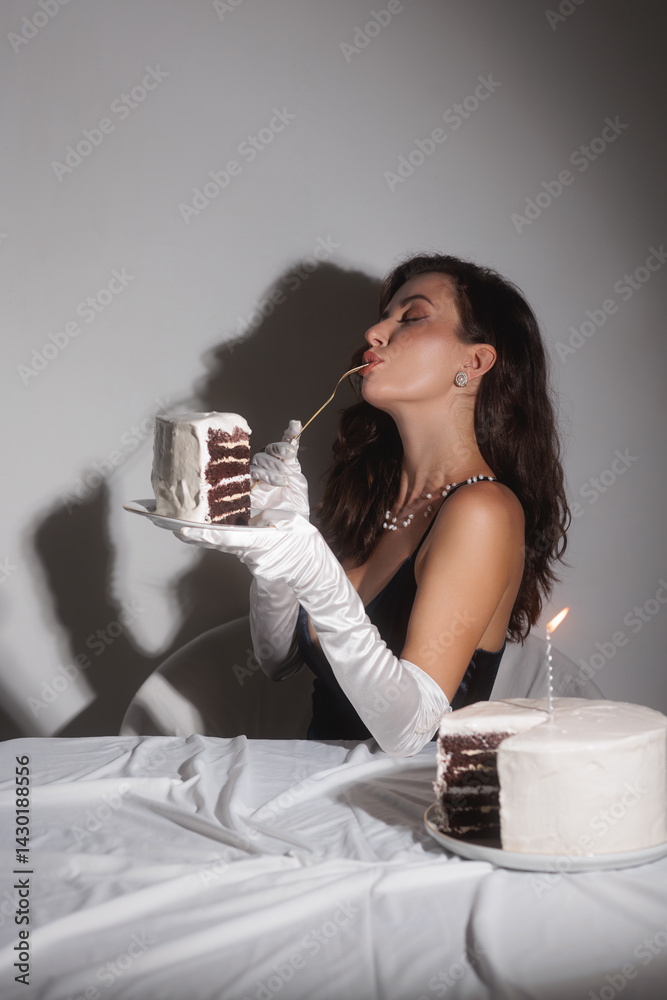 A glamorous woman in white gloves and a low-cut black top enjoys a slice of birthday cake. This high-quality stock photo is perfect for promoting luxury, elegance, and sophistication in fashion and