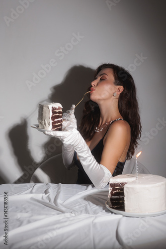Obraz na płótnie A glamorous woman in white gloves and a low-cut black top enjoys a slice of birthday cake. This high-quality stock photo is perfect for promoting luxury, elegance, and sophistication in fashion and w salonie