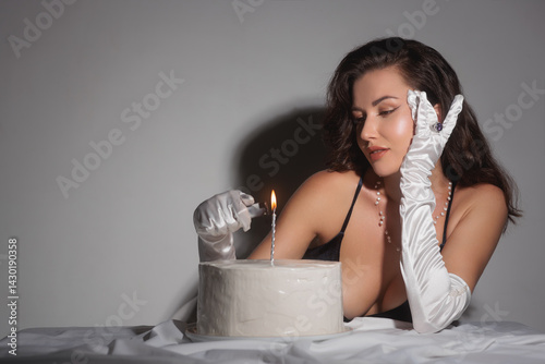 Obraz na płótnie Glamorous woman in white satin gloves lighting a candle on a cake. Ideal for luxury lifestyle, celebration, and fashion themes, highlighting elegance, charm, and sophistication. w salonie