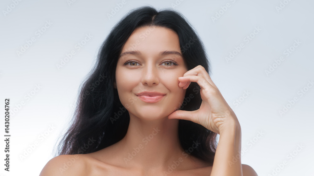 Young smiling woman gently creates a half-heart gesture with her hand near her face, symbolizing skincare, self-love, and positivity. Ideal for beauty, wellness, and cosmetic branding.