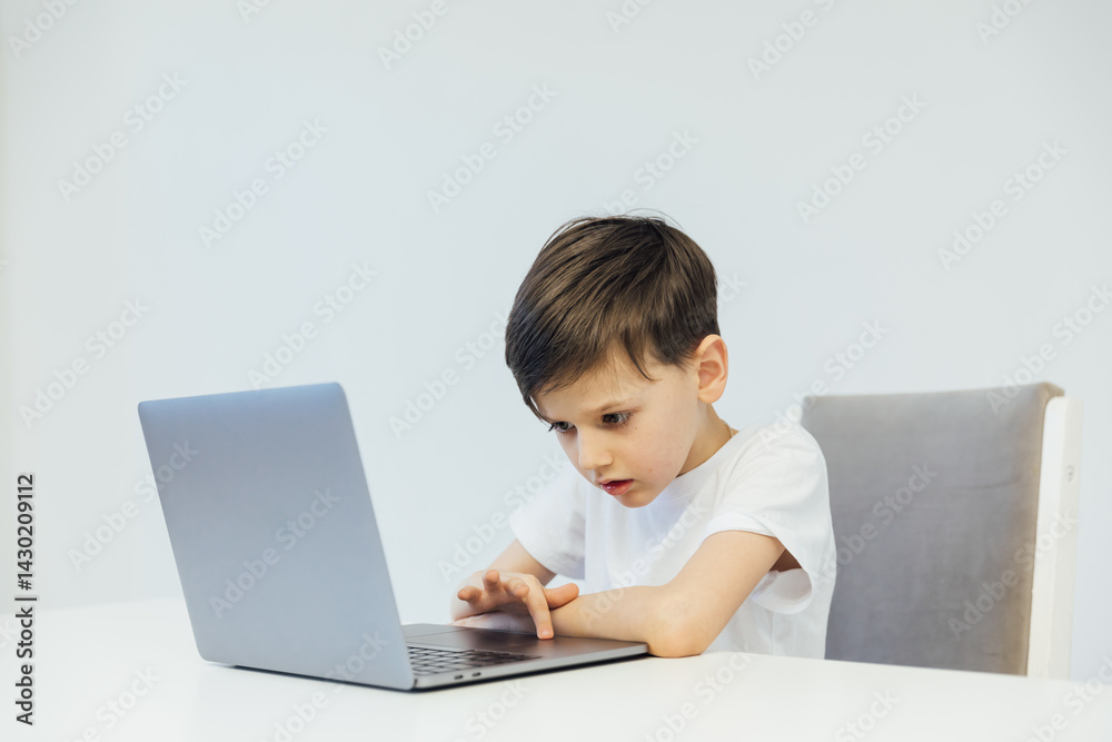 Boy doing homework at desk with laptop Boy doing homework at desk with laptop