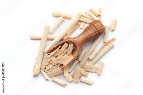 A wooden scoop filled with organic Lemongrass (Cymbopogon flexuosus), placed on a heap of lemongrass, isolated on a white background. photo