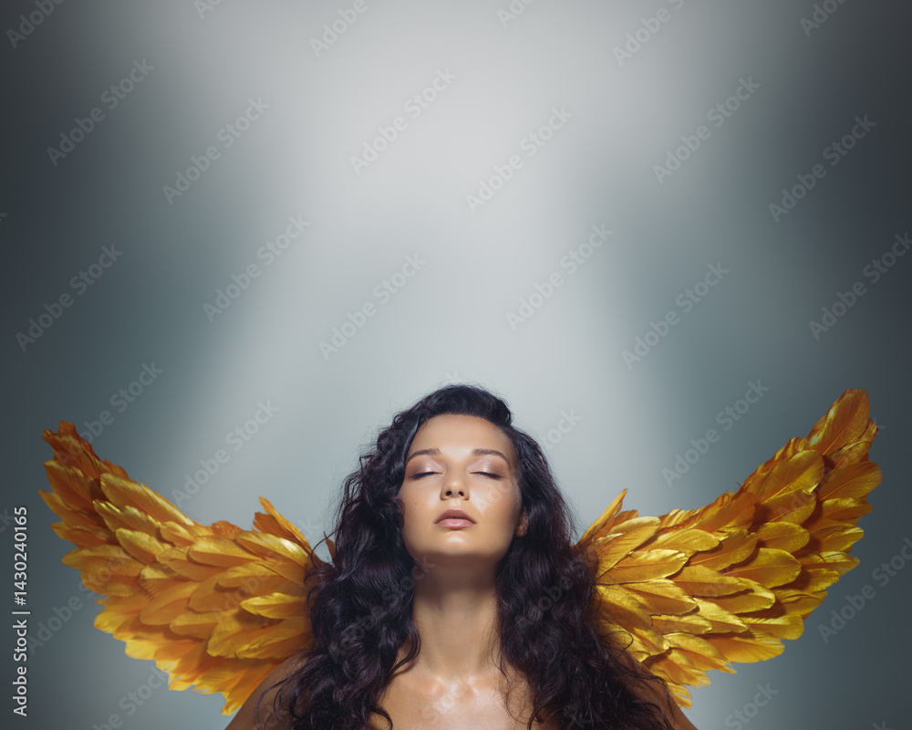 Elegant brunette model with glowing skin and golden angel wings poses with closed eyes under soft light. A refined fantasy beauty banner with clear space for text and branding use.