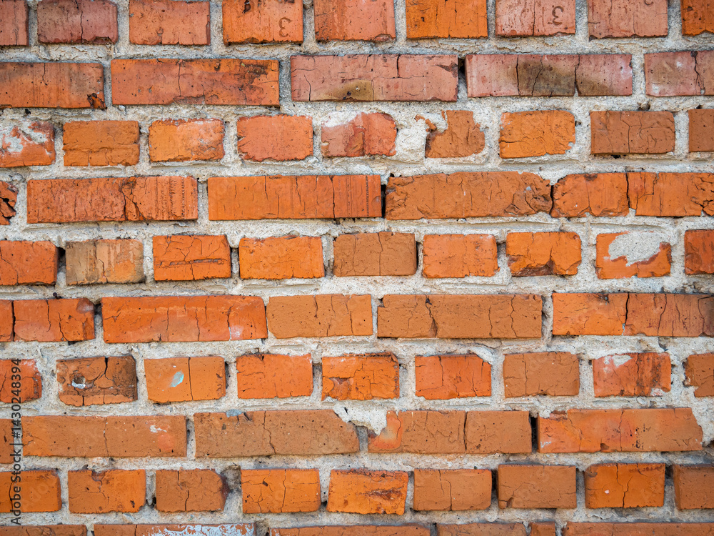 Obraz premium Weathered red brick wall with exposed mortar and cracks