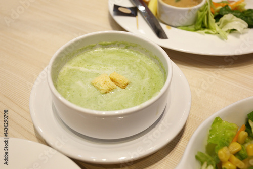 Obraz na płótnie Green spinach soup in a white bowl with a saucer on the dining table. w salonie