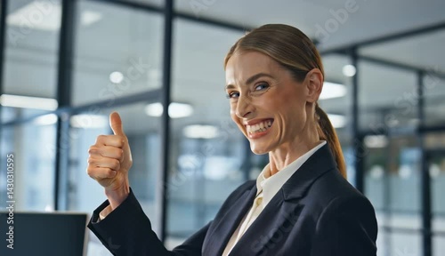 A professional businesswoman giving a thumbs up while smiling confidently in a modern office
