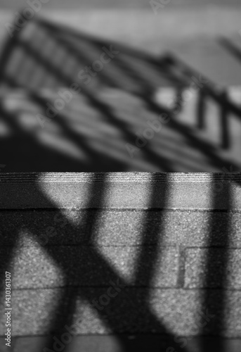 black and white of shadows on concrete stairway black lines on grey bricks vertical abstract image with room for type lines pattern and shape shades of grey foreground in focus background blurry 