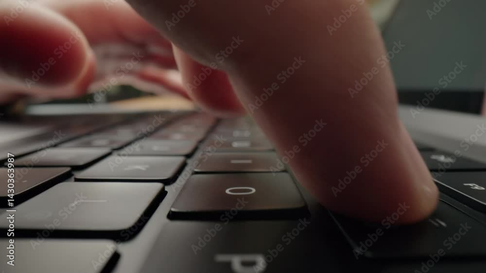 Close-up of mans fingers typing on laptop keyboard in modern café