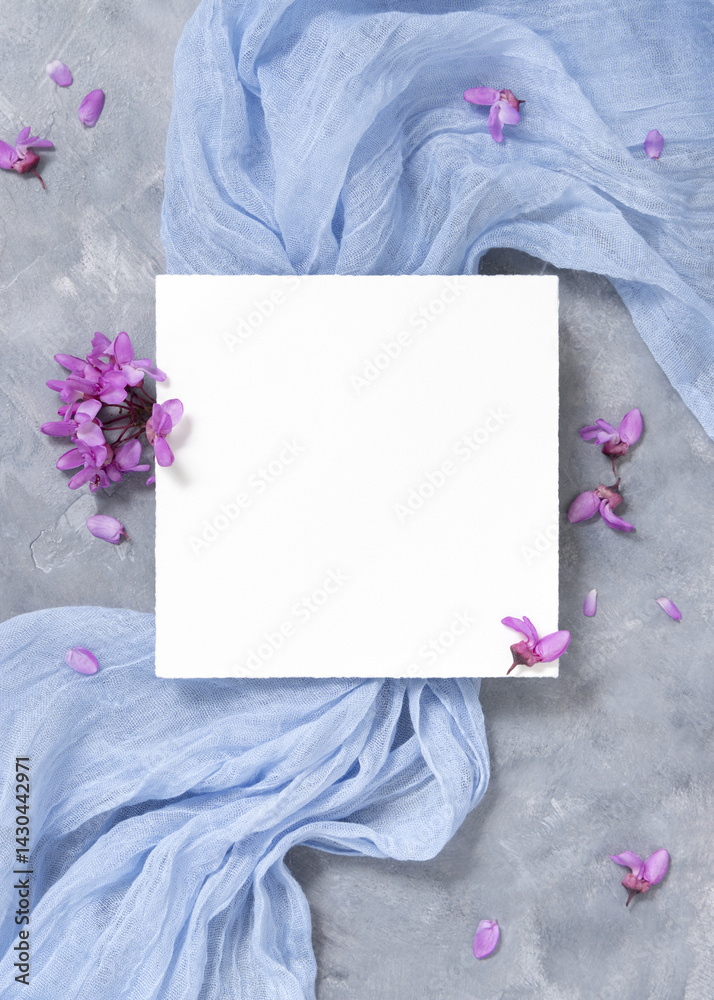 Blank card on fabric near wild purple flowers top view on gray, spring wedding mockup