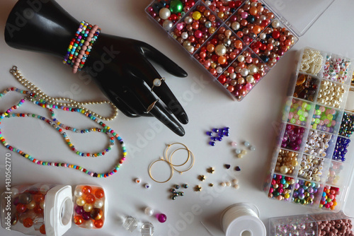 Obraz na płótnie Hand figurine, colorful friendship bracelets, necklaces, various beads and DIY supplies on the table. Making jewelry at home. Flat lay. w salonie