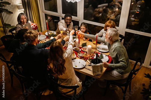 Canvas-taulu A group of Black and White people, including children, adults, and elderly people, gathers around a candlelit wooden dinner table