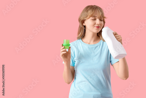 Young woman smelling laundry detergent on pink background
