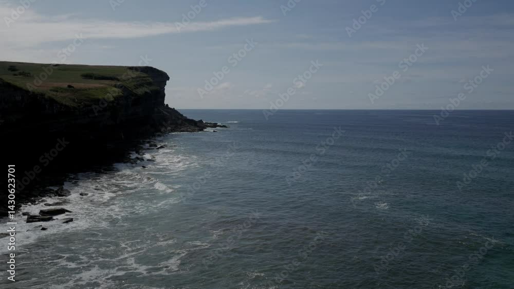 Stunning aerial view of El Bolao cliff with the serene ocean below in Cobreces, Spain Stunning aerial view of El Bolao cliff with the serene ocean below in Cobreces, Spain
