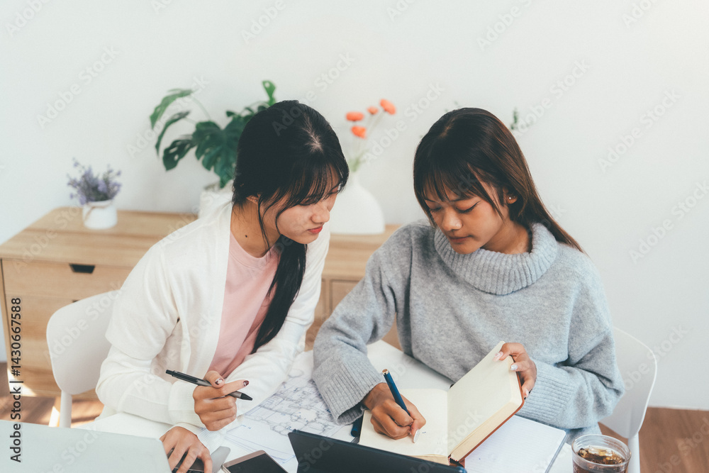 Female higher education student using laptop and studying book in home, Online learning. Female higher education student using laptop and studying book in home, Online learning.