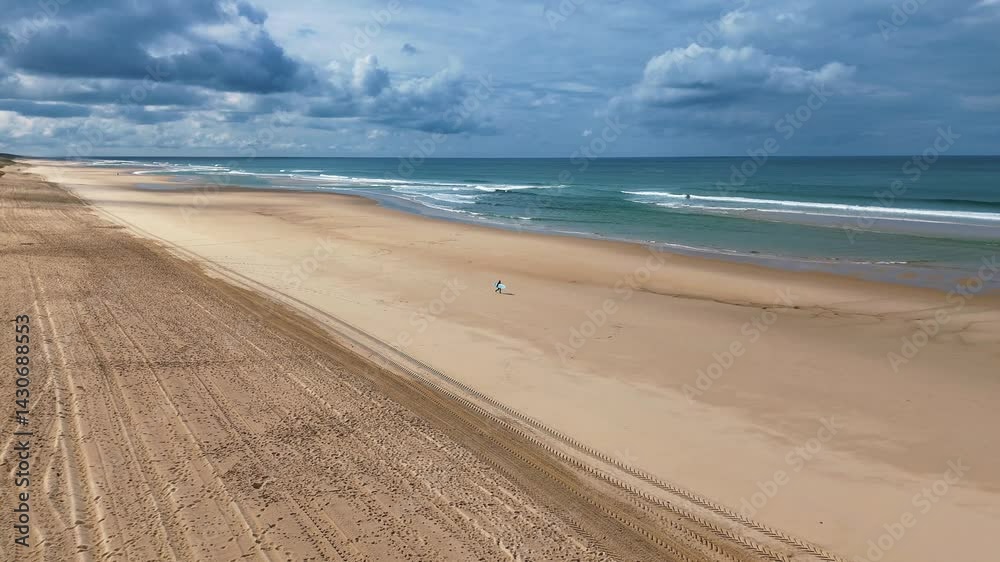 Surfeur solitaire planche sous le bras devant océan bleu vagues battantes