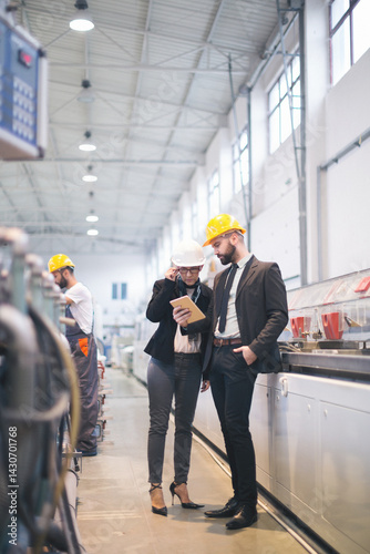Quality inspectors team and workers at factory using machines