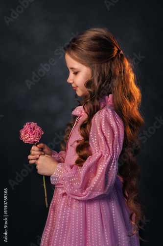 Obraz na płótnie Beautiful girl in a pink dress with a peony flower on a dark background. Romantic, festive image w salonie