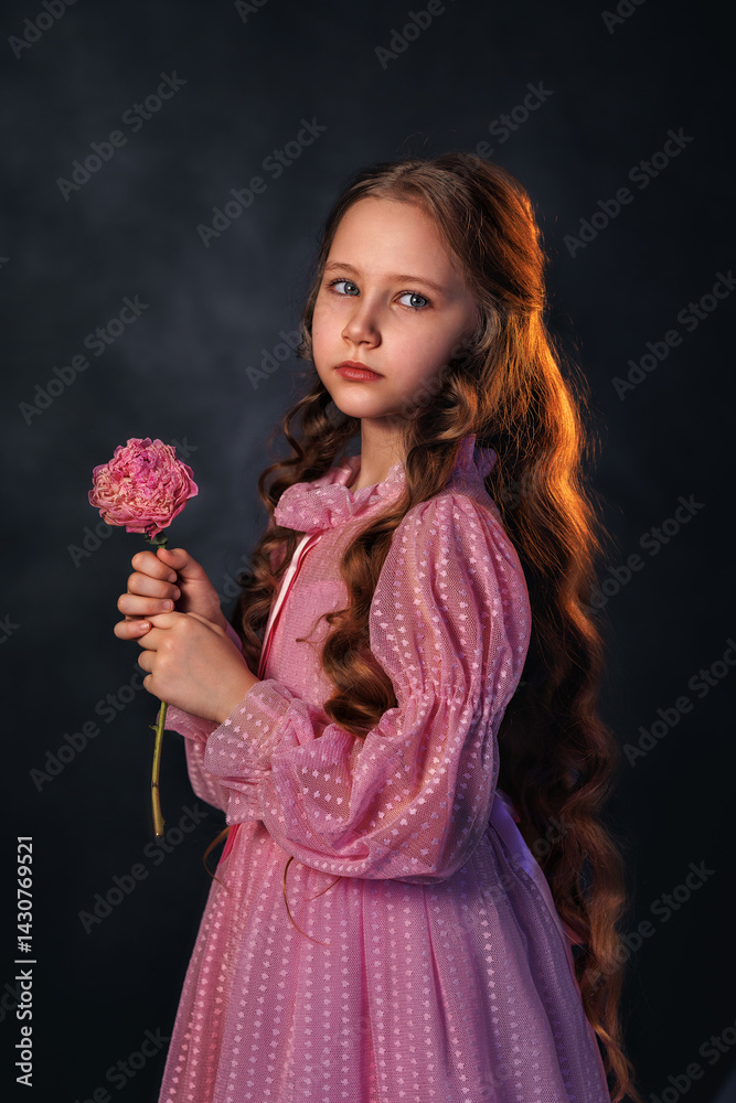 Beautiful girl in a pink dress with a peony flower on a dark background. Romantic, festive image